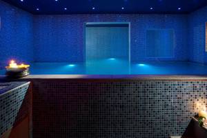Innenpool im Blue Bay Resort mit blauer Beleuchtung und brennenden Kerzen.