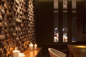 Behandlungsraum im Aqua Blu Boutique Hotel & Spa mit gemusterter Wand, drei brennenden Kerzen und einem Mann, der eine Massage durchführt.