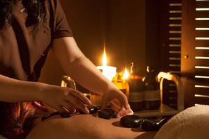 Massage im Aqua Blu Boutique Hotel & Spa mit Kerzenlicht und steinernen Massagewerkzeugen.