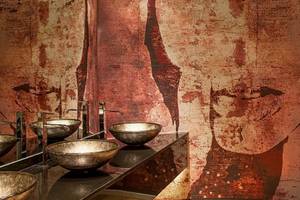 Badezimmer im Aqua Blu Boutique Hotel & Spa mit kupferfarbenen Waschbecken und einer Wandverkleidung aus oxidiertem Kupfer.