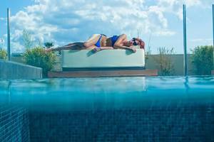 Eine Frau liegt entspannt auf einer Liege im Pool des Aqua Blu Boutique Hotel & Spa.