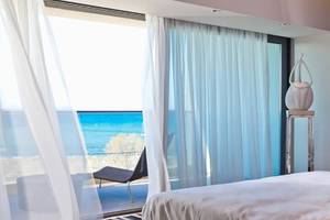 Zimmer mit Meerblick im Aqua Blu Boutique Hotel & Spa mit weißen Vorhängen und einem Bett.