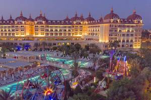 Luftaufnahme des Royal Alhambra Palace Resorts mit beleuchtetem Gebäude, Swimmingpool und Vergnügungspark.