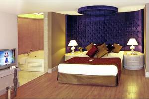 Ein elegantes Hotelzimmer mit einem Bett, Fernseher, Nachttischen und einem Whirlpool.