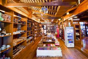 Innenansicht des Santhiya Koh Phangan Resort & Spa Shops mit Holzboden und Regalen voller Produkte.