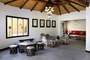 Loungebereich im Al Hamra Village mit Möbeln, Lampen und Porträts an der Wand.