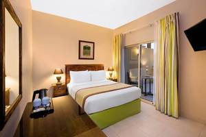 Doppelbettzimmer im Al Hamra Village Hotel mit Balkon und Fernseher.