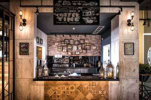 Innenansicht der Kaffeebar im Fodele Beach & Water Park Holiday Resort mit Theke, Kaffeemaschinen und Dekor.