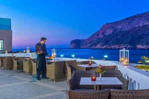 Terrasse des Fodele Beach & Water Park Holiday Resort mit Blick auf das Meer und die Berge bei Abendstimmung