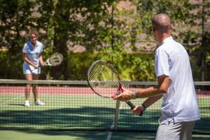 Tennisspieler auf Tennisplatz im Freien mit Frau im Hintergrund