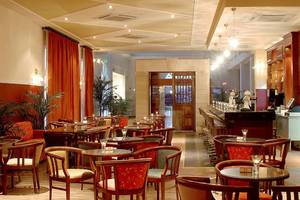 Innenansicht des Restaurants im Aktea Beach Village Hotel mit runden Tischen und Stühlen.