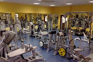 Fitnessstudio im Aktea Beach Village Hotel mit vielen Trainingsgeräten und gelben Wänden