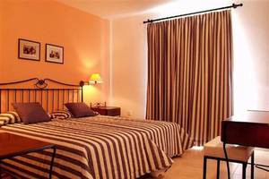 Doppelzimmer im Aktea Beach Village Hotel mit zwei Betten, Tisch, Stuhl, Lampe und Wanddekoration.
