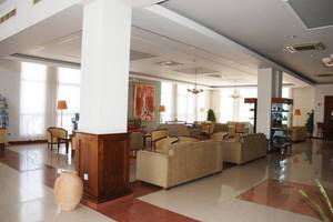 Aktea Beach Village Hotellobby mit Sofas, Lampen und Gemälden an der Wand.