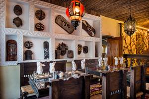 Innenbereich des Bahari Zanzibar Restaurants mit afrikanischen Masken und Lampen an der Wand.