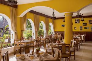 Innenansicht des Restaurants im Bahari Zanzibar Hotel mit gelben Wänden und Holzmöbeln.