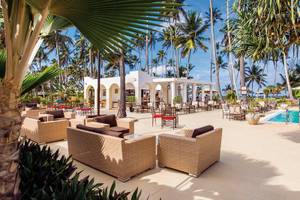 Außenbereich des Bahari Zanzibar Hotels mit Lounge-Sesseln, Tischen und Palmen.