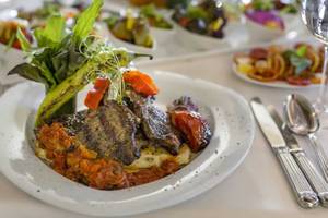 Speiseplatte im Royal Wings Hotel mit gegrilltem Fleisch, Tomaten und Salat.