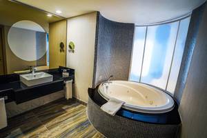 Badezimmer im Royal Wings Hotel mit einer Badewanne und einem Spiegel.