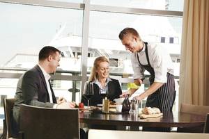 Ein Kellner serviert ein Essen in einem Restaurant mit Blick auf ein Schiff.