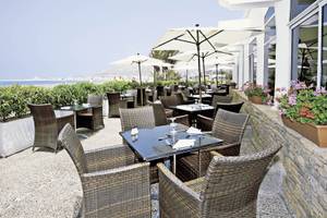 Außenterrasse des Royal Decameron Tafoukt Beach Hotels mit Tischen, Stühlen und Sonnenschirmen.