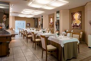Innenansicht des Restaurants des Grand Teguise Playa Hotels mit gedeckten Tischen und Gemälden an der Wand.
