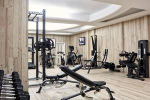 Fitnessraum im Myconian Imperial Hotel mit Holzboden und verschiedenen Trainingsgeräten.