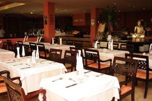 Innenansicht des Restaurants im Grand Palladium Jamaica Resort & Spa mit gedeckten Tischen, Stühlen und einem Buddha-Standbild.