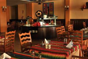 Restaurant im Grand Palladium Jamaica R. & Spa mit farbenfrohen Tischdecken und Holzmöbeln.