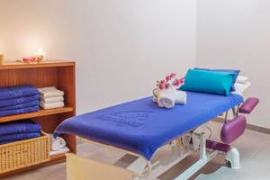 Massageraum im Aparthotel Fontanellas Playa mit blauer Decke, Kissen, Kerzen und einem Regal mit Handtüchern.