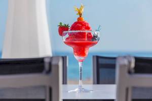 Roter Cocktail in einem Glas mit Blick auf den Strand und das Meer