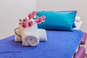 Ein Hotelzimmer mit einem blauen Bett, blauen Kissen und Orchideen auf dem Bett.