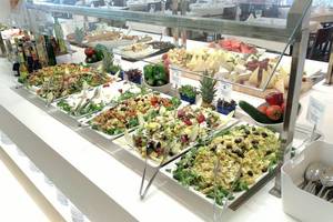 Buffet mit verschiedenen Salaten und Gerichten, darunter Obstsalat, gemischte Salate und Käseplatten.