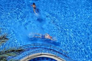 Zwei Leute schwimmen im Pool vom Cosmopolitan Hotel, eine Frau oben und ein Mann unten.