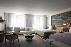 Suite-Zimmer im 1 Hotel South Beach mit zwei Betten, Wohnzimmermöbeln und einer Holzwand.