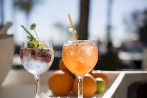 Zwei Cocktails auf einer Hotelterrasse mit Orangen im Hintergrund.