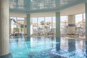 Pool im Hipotels Flamenco Hotel mit Loungestühlen und Sonnenschirmen.