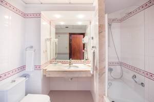 Badezimmer des Hipotels Flamenco mit Waschbecken, Spiegel und Dusche.