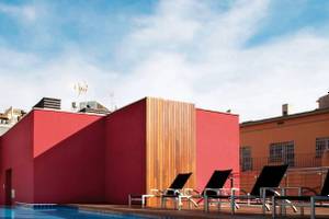 Pool auf der Dachterrasse des Barcelona Catedral Hotels mit roten Wänden und Lounge-Liegestühlen