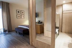 Innenansicht eines Zimmers im Barcelona Catedral Hotel mit Bett, Ottomane und Badezimmerspiegel.
