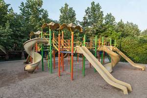 Spielplatz im Hotel Sultan of Side mit Rutschen und Klettergerüst unter Bäumen.