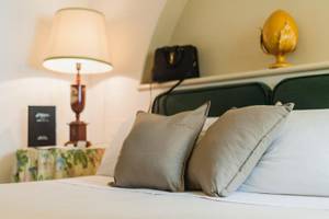 Doppelbett mit zwei Kissen, Lampen und Taschen im Zimmer im Hotel Il Melograno