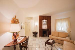 Wohnzimmer im Hotel Il Melograno mit Sofas, Kamin, Tisch und Stuhl.