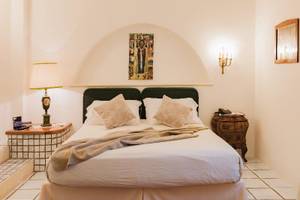Schlafzimmer im Il Melograno Hotel mit zwei Betten, weißen Laken, Kissen, Lampen und Gemälden an der Wand.