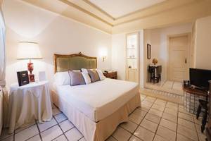 Hotelzimmer von Il Melograno mit einem großen Bett, Kissen, Nachttisch mit Lampe und Fernseher.