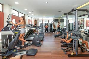 Fitnessstudio im Blue Lagoon Resort mit Läuferinnen auf Laufbändern und Männern, die Gewichte heben.