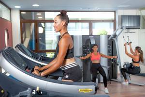 Frauen trainieren im Fitnesscenter des Blue Lagoon Resorts auf Laufbändern und mit Gewichten.