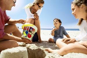 Familie im Costa Lindia Beach Resort am Strand mit Sandburg und Eistüte