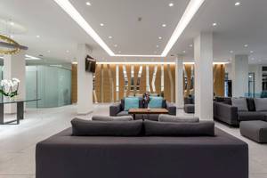 Innenansicht der Lobby des Acharavi Beach Hotel mit modernen Möbeln und Holzelementen.