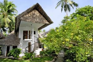 Außenansicht des Severin Sea Lodge tropischen Hauses mit Strohdach, umgeben von Pflanzen und Bäumen.